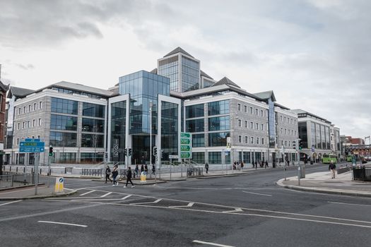Dublin, Ireland - February 12, 2019: View of the modern building of the Irish commercial bank Ulster Bank next to the River Liffey where people walk on a winter day