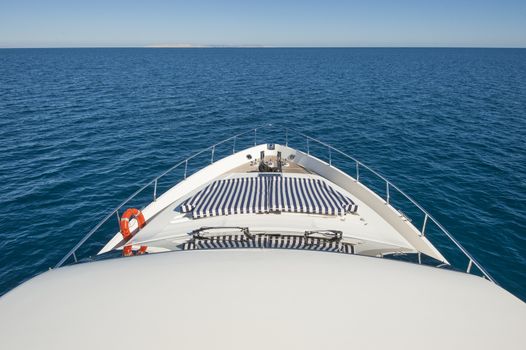 View over tropical ocean from the bow of a luxury large private motor yacht with horizon