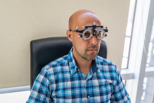 vision measurement by optometrist at clinic, young man as patient.