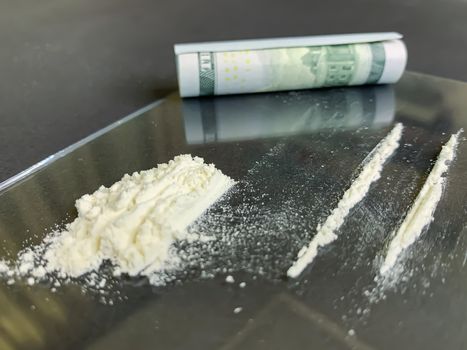 Close up of rolled 100 us dollars and 2 lines of cocaine on a gray background. Illegal drug addiction. Stock image.