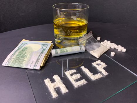 Pills; us dollar banknotes; whiskey and cocaine; on a gray background. Stop drugs concept. A word "help" written with cocaine. Stock image.