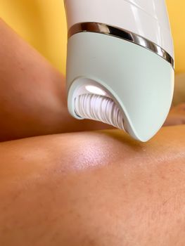 Electric depilator epilator in a female hand. Hair removal from the legs. Real life. Close-up.