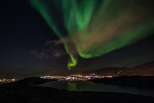 Massive green Aurora Borealis Northern lights shining over the lake and Nuuk city, Greenland