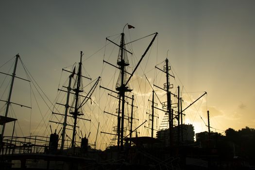 Silhouettes of ship masts on the sunset sky background. Stock image. 
