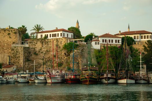 Beautiful yachts and touristic boats in the marina, port of Antalya old town Kaleici, Turkey. Old historical stone castle wall on the background. Stock image.