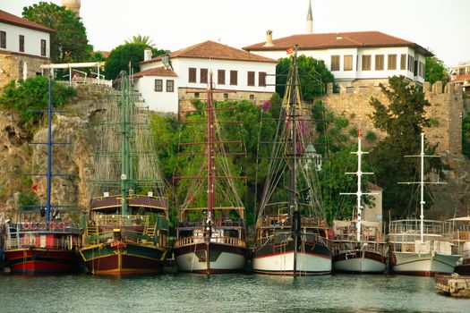 Beautiful yachts and touristic boats in the marina, port of Antalya old town Kaleici, Turkey. Old historical stone castle wall on the background. Stock image.