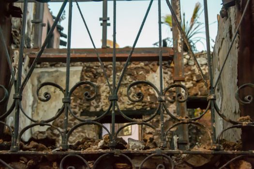 Ruins of burned ancient historical 2 floors house after fire disaster accident in old town of Antalya Kaleici Turkey. Stock image of heaps of ash and arson, collapsed roof. View from forged window grill