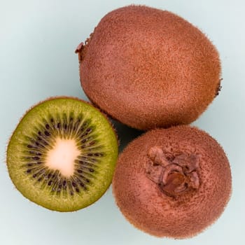 Fresh ripe whole and half kiwi fruit on a light blue background. Flat lay