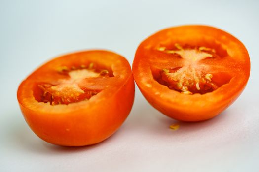 A close up of a half red tomato in a white background