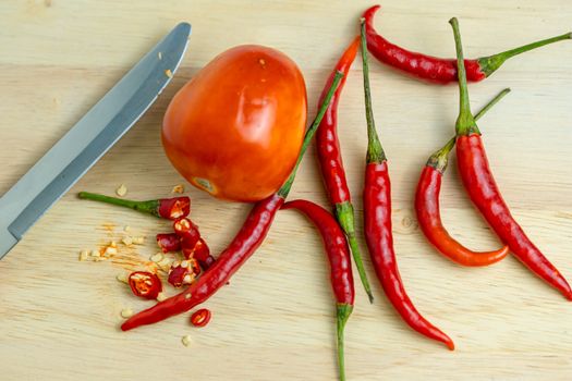 Close-up shot of chili and red tomatoes on a wooden cutting board background. Fresh food ingredients concept.