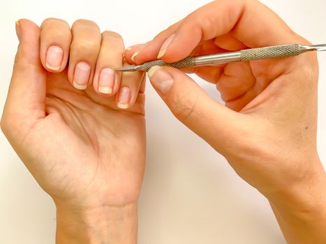 Female woman doing manicure at home on a white background. Self manicure close up