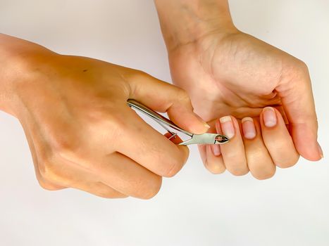 Close up of hands. Self manicure at home trimming cuticles on white background. Manicure and skin care. 