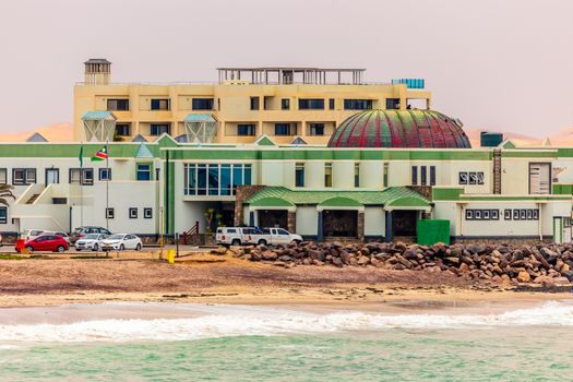 Sea waves, coastline cars and buildings on the street of Swakopmund German colonial town, Namibia