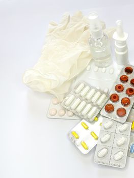 Different medicines: tablets, pills in blister pack, medications drugs, medical gloves, mask, syringe, thermometer, spray, sanitizer on a white background. Vertical photo with space for text