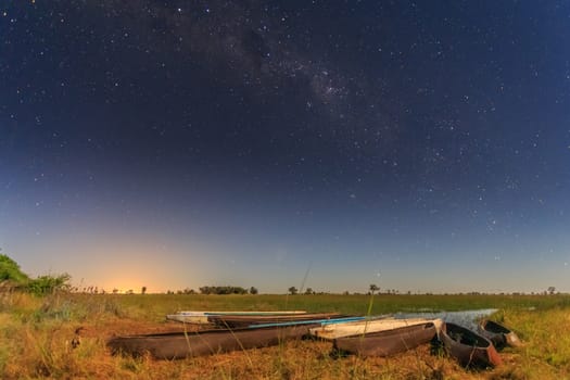 Botswanian local mokoro boats under the starlite sky, on the shore of delta Okavango river, Botswana