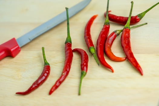 Close-up of chilli and red knives on a wooden floor, meat, fresh food ingredients concept