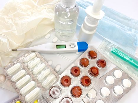 Different medicines: tablets, pills in blister pack, medications drugs, medical gloves, mask, syringe, thermometer, spray, sanitizer on a white background. Horizontal photo