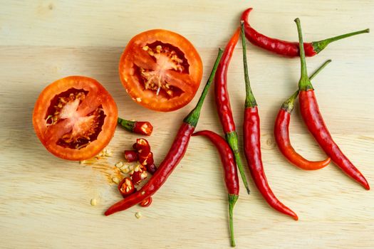 Close-up shot of chili and red tomatoes on a wooden cutting board background. Fresh food ingredients concept.