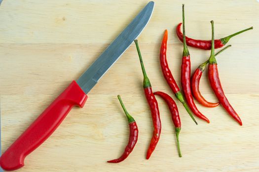 Close-up of chilli and red knives on a wooden floor, meat, fresh food ingredients concept