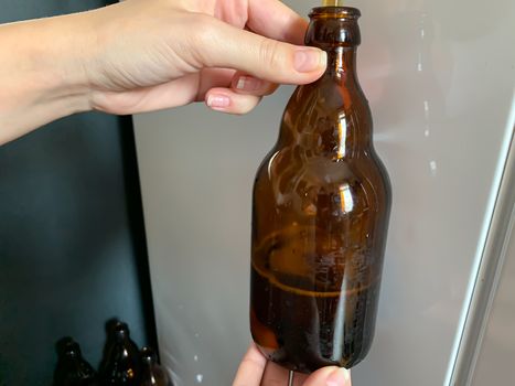 Craft beer brewery. Filling brown glass beer bottle at home. Self made beer. Horizontal image
