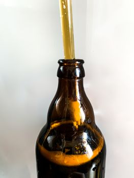 Craft beer brewery. Filling brown glass beer bottle at home. Self made beer. Close up vertical image on a white background