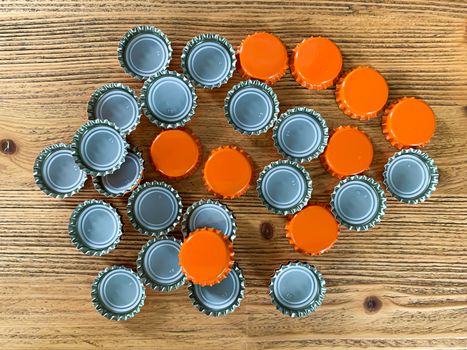 Many orange beer lids, bottle corks tops on a wooden texture top view horizontal image 