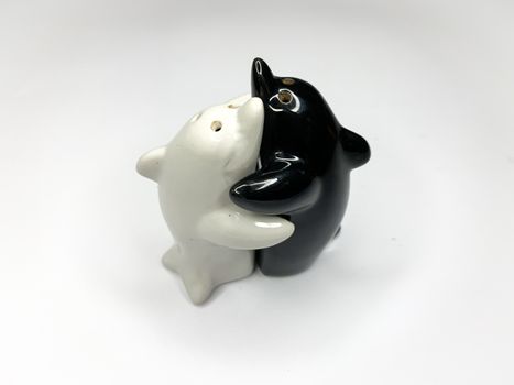 Black and white yin yang dolphin shaped salt and pepper shakers hugging each other on white background