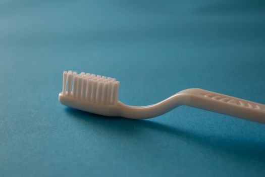 Close up macro plastic white tooth brush on blue background dental hygiene