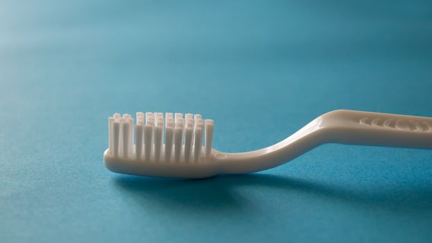 Close up macro plastic white tooth brush on blue background dental hygiene