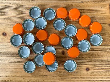 Many orange beer lids, bottle corks tops on a wooden texture top view horizontal image 