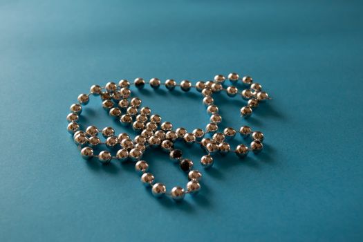 Close up string of silver gray beads on blue background