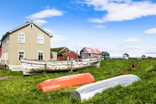 Fishing village living wooden houses and boats in front with blue sky in the background, Flatey island, Iceland