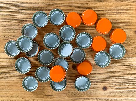 Many orange beer lids, bottle corks tops on a wooden texture top view horizontal image 