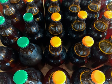 A lot of home brewery self made beer. Many brown glass craft beer bottles with green and orange corks, close up top view on a wooden texture horizontal image.