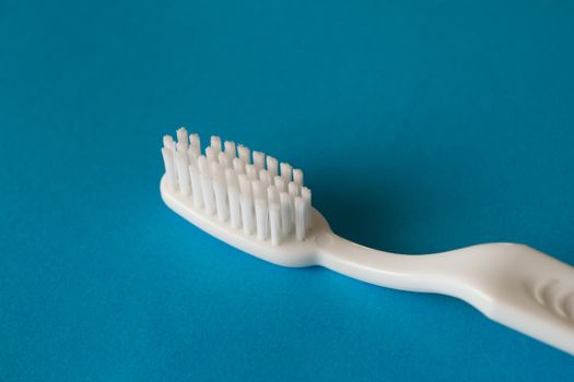 Close up macro plastic white tooth brush on blue background dental hygiene