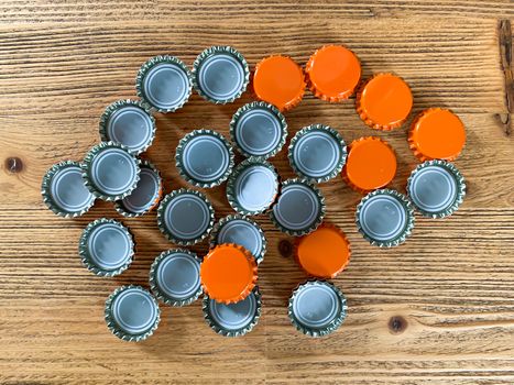 Many orange beer lids, bottle corks tops on a wooden texture top view horizontal image 