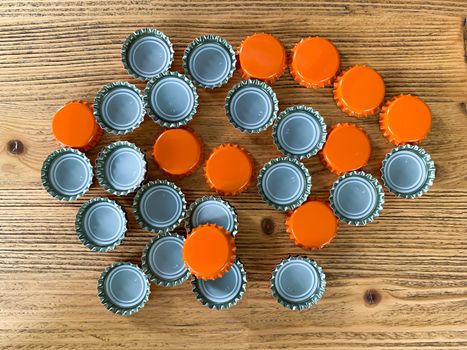 Many orange beer lids, bottle corks tops on a wooden texture top view horizontal image 