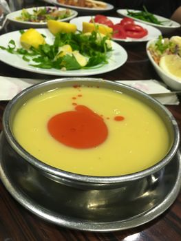 Traditional Turkish yellow lentil soup in metal bowl with salad and vegetables