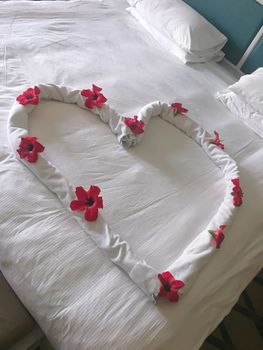 Heart with flowers decor on a bed in hotel room

