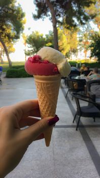 Colorful ice cream in a waffle cone in a girl's hand