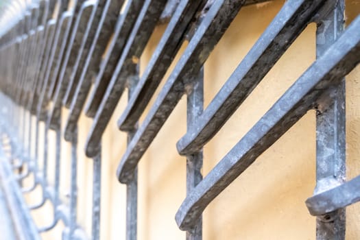 Wrought-iron work on a yellow wall for protection and decoration made of moulded rods welded together.