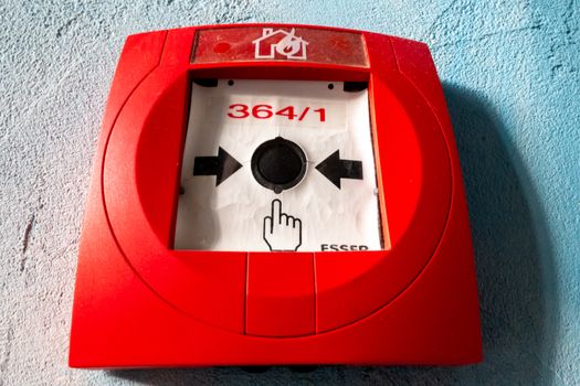 Krausnick, Brandenburg/Germany - 11.01.2020: A red fire alarm with numbering, pictograms for hand and burning house and a button with arrows pointing to instructions.