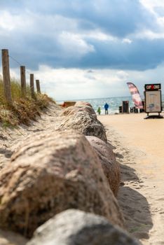 Fehmarn, Schleswig-Holstein/Germany - 05.09.2019: A path over a dune to the beach with tourist facilities in the background and as path border stones and a fence at the Baltic Sea island Fehmarn.