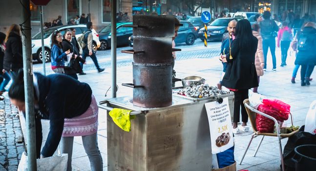 Porto, Portugal - 30 November 2018: Street vendors of roasted chestnuts in front of Sao Bento station in the city center on a fall day