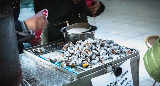 Porto, Portugal - 30 November 2018: Street vendors of roasted chestnuts in front of Sao Bento station in the city center on a fall day