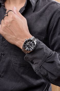 The man posing with dive watch with stainless steel bracelet.