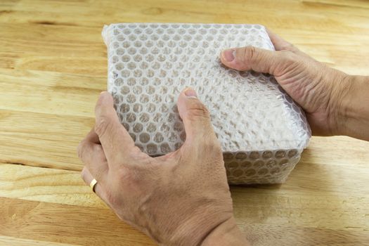 hand of man hold Bubbles covering the box by bubble wrap for protection product cracked  or insurance During transit - 
