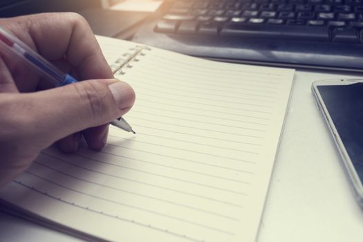 male hand writing in notebook with pen,
left hand