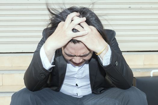 Upset asian businessman 20s tired from work sitting at stairs, unemployment, fired from job, disappointed