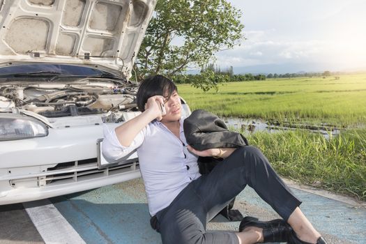 Young asian business man has Broken Down car and sitting calling for help